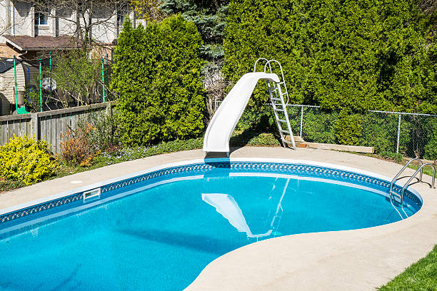 White water slide by a swimming pool in a backyard.